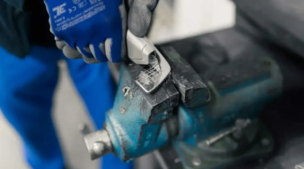 Auf dem Bild sind Hände mit Arbeitshandschuhen zu erkennen, welche Stahl und Metall an einer Maschine bearbeiten