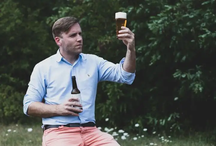 Herr Bach von der Braumanufaktur Bach hält eine Flasche Bier und ein Glas Bier in den Händen.