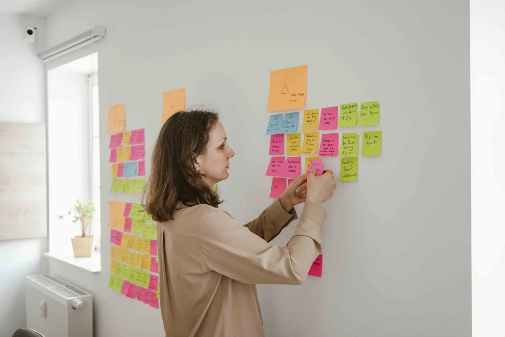 Eine Frau klebt bunte Zettel an eine Wand
