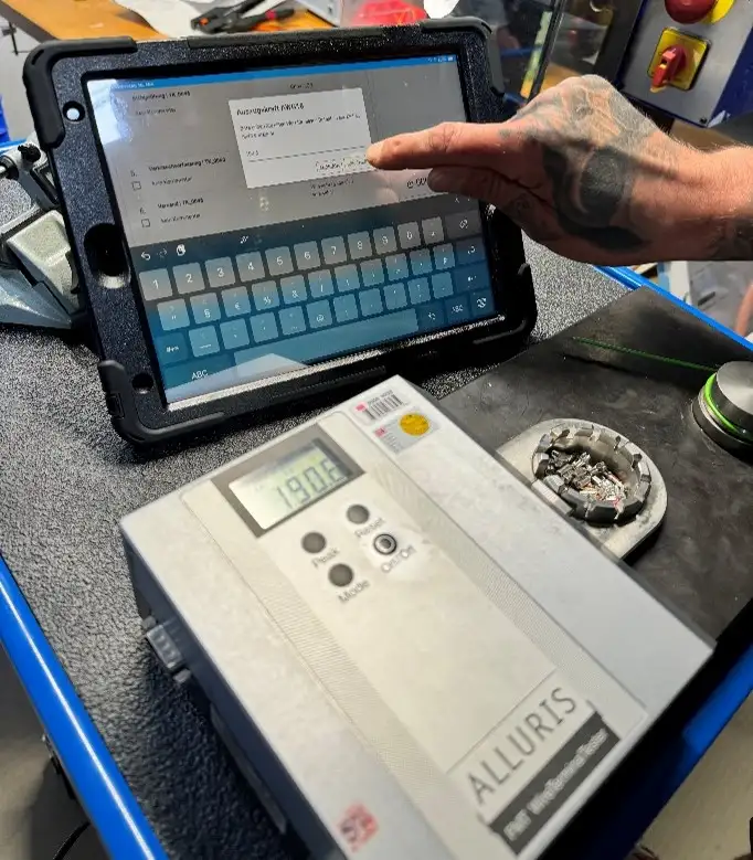 Es ist en Tablet im Einsatz zu sehen, ein Mitarbeitender bedient das Tablet um einen Produktionsauftrag zu speichern.