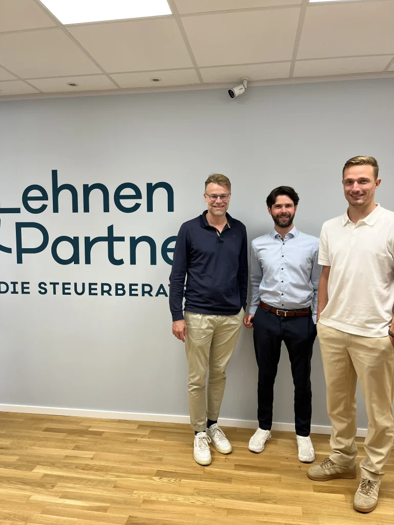 Auf dem Foto sind zwei Mitarbeiter des Mittelstand-Digital Zentrum Kaiserslautern und eine Mitarbeiter von Lehnen und Partner vor dem Logo der Unternehmung zu sehen.