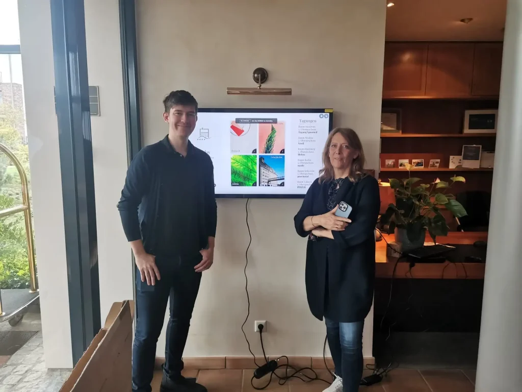 Ein Mann und eine Frau stehen vor dem digitalen Infoboard